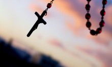 Rosary with cross over sunset sky