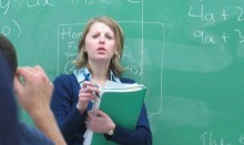 Teacher in front of green board with equations on