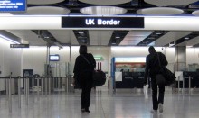 Two people at Heathrow walking to UK Border sign